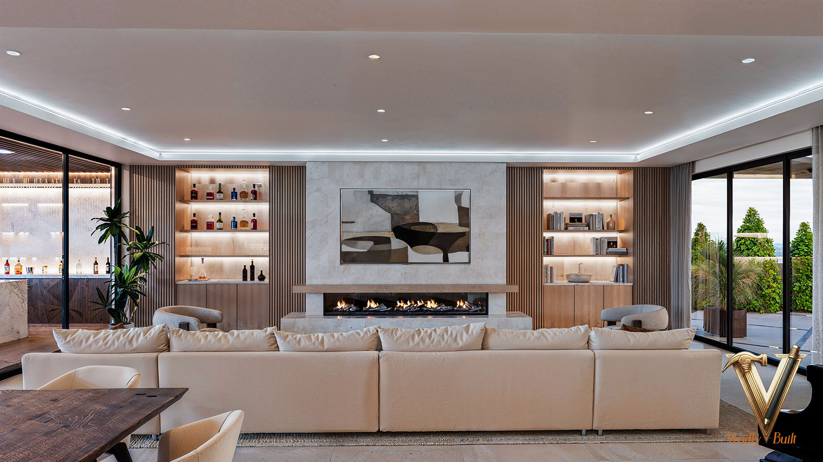 Great room with see-through linear fireplace, wood-slat walls, backlit stone shelving and wine display — Modern Estate, Palos Verdes